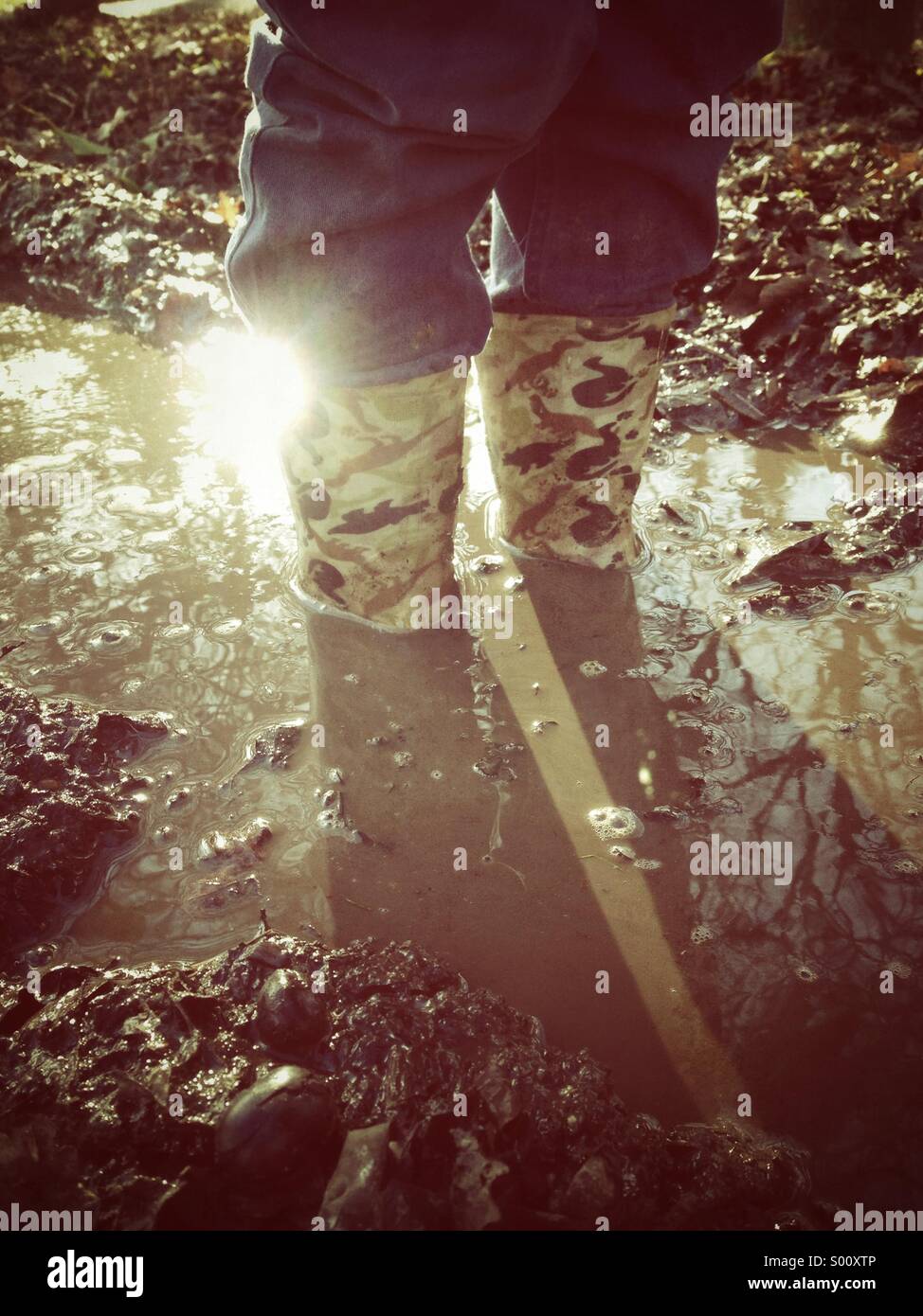 A person in wellies standing in a muddy puddle - Smartphone Captured Stock Image