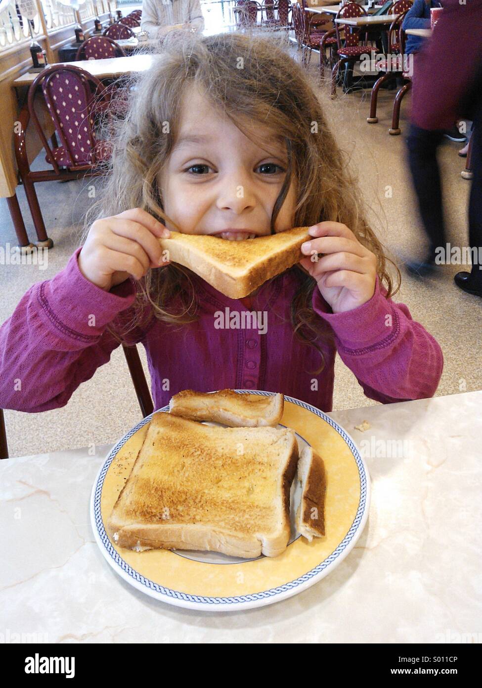 Girl eating toast in a cafe Stock Photo Alamy