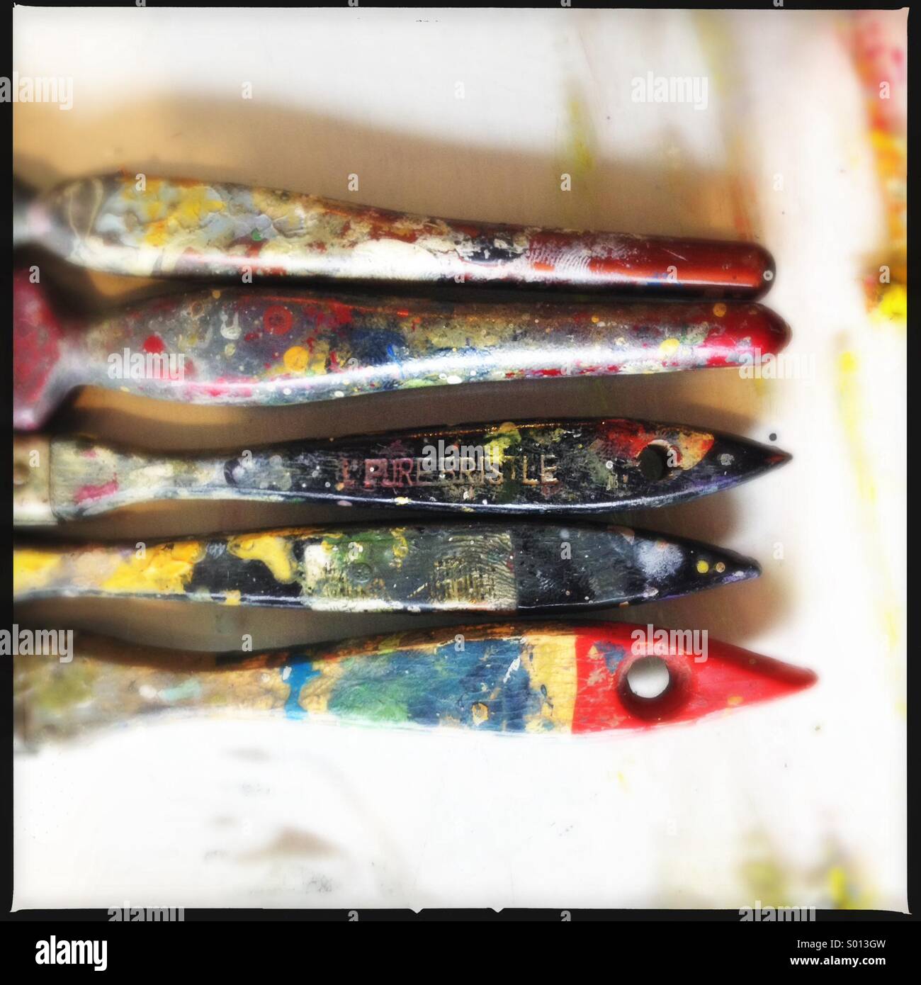 Colourful artist's paintbrush handles in a row. Stock Photo