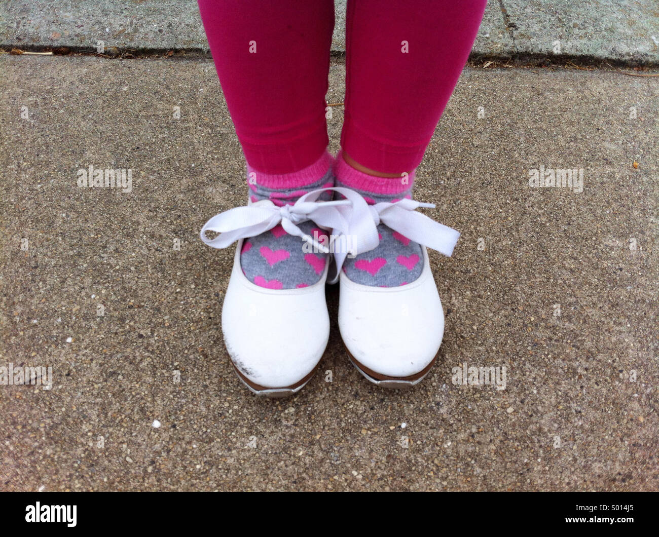 Little girl in white tap dancing shoes with bows and heart socks Stock Photo