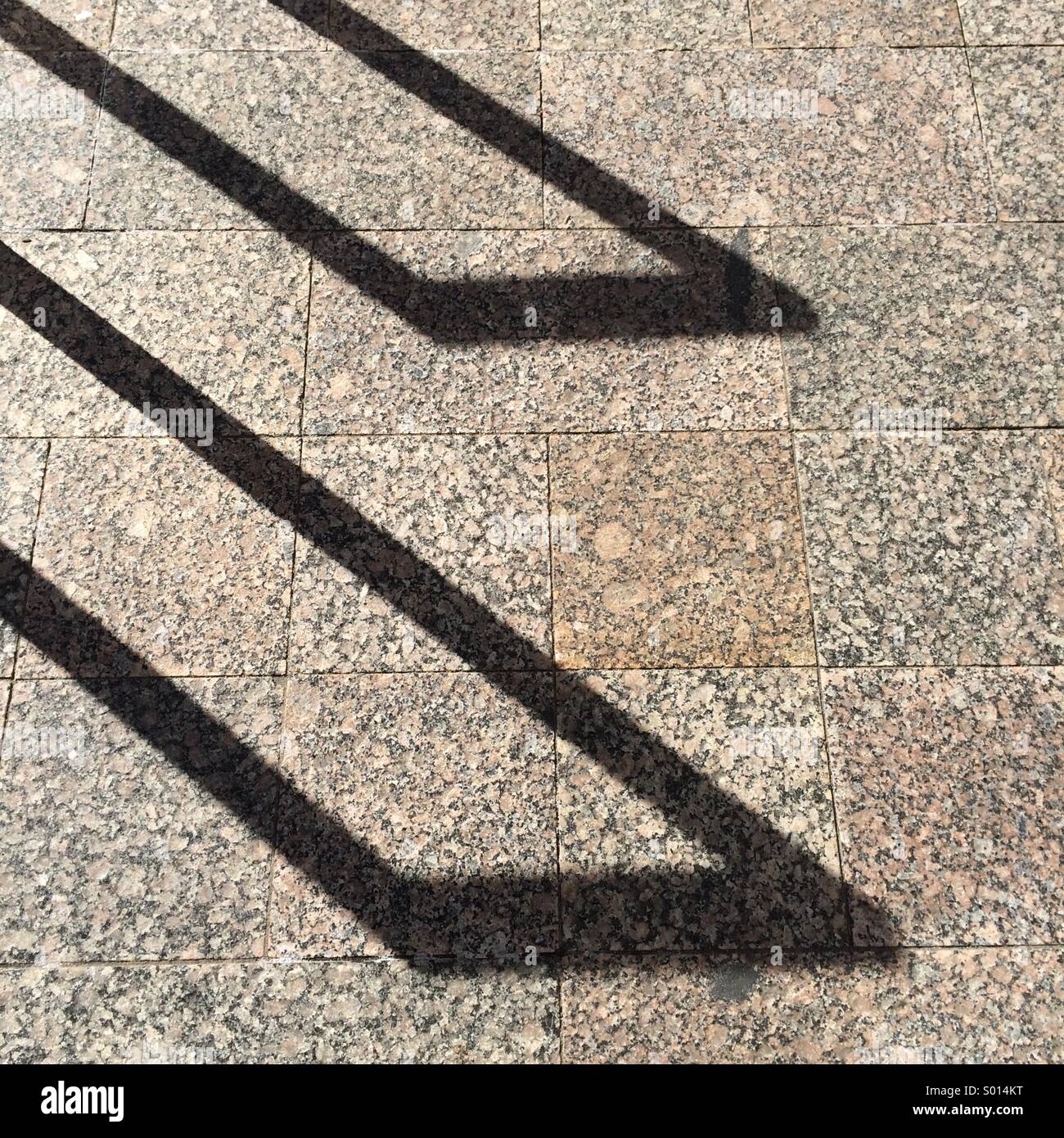 Rectangles indicate the direction of the sun on an early city morning. Empty bike racks cast geometric shadows. Stock Photo