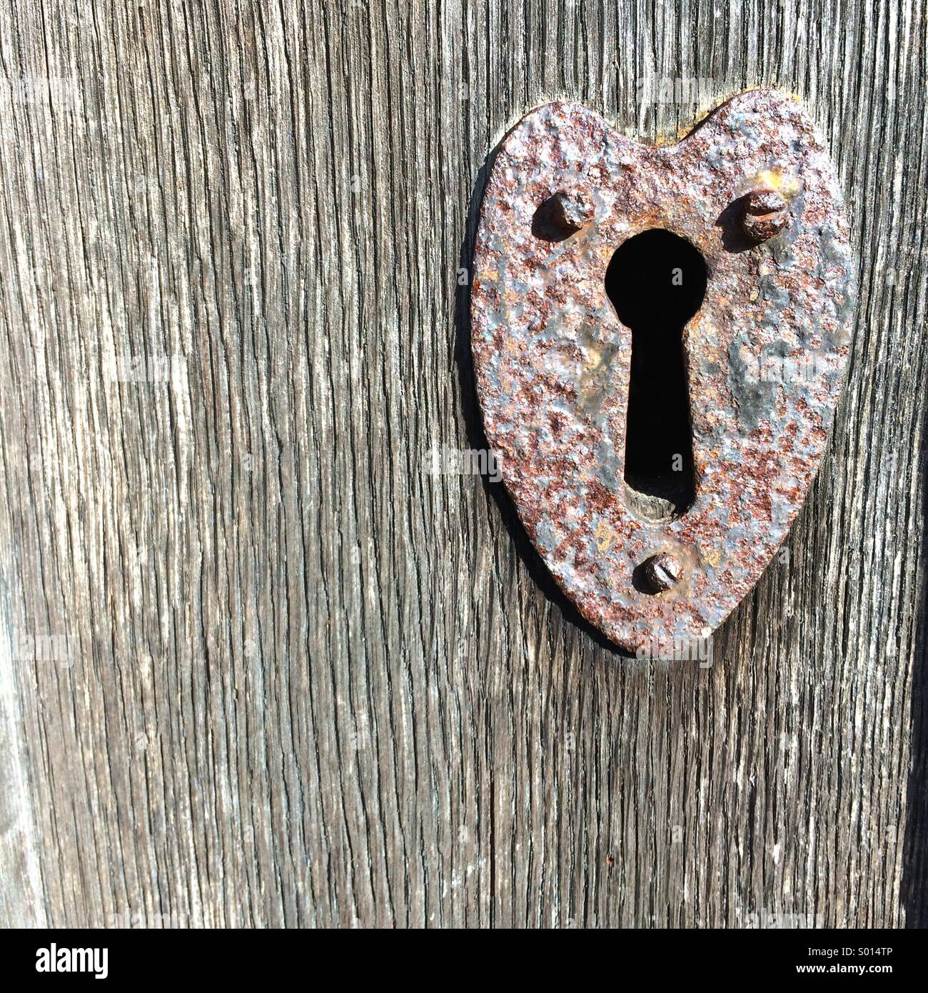 Heart shaped door key hole plate on a vintage wooden door Stock Photo