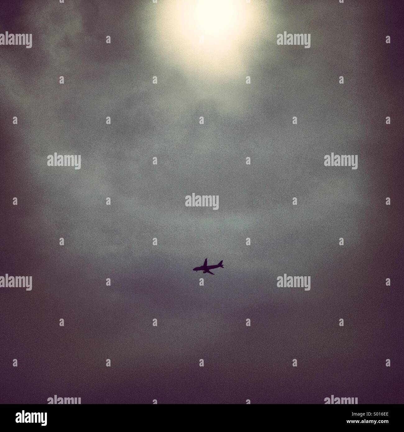 Airplane in  cloudy sky with the sun hidden - Smartphone Captured Stock Image