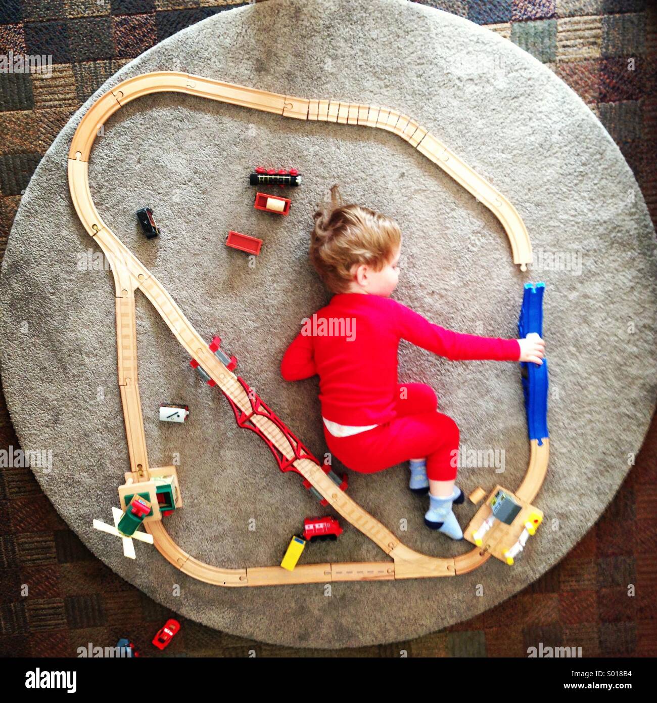 Little boy playing with a toy train track Stock Photo