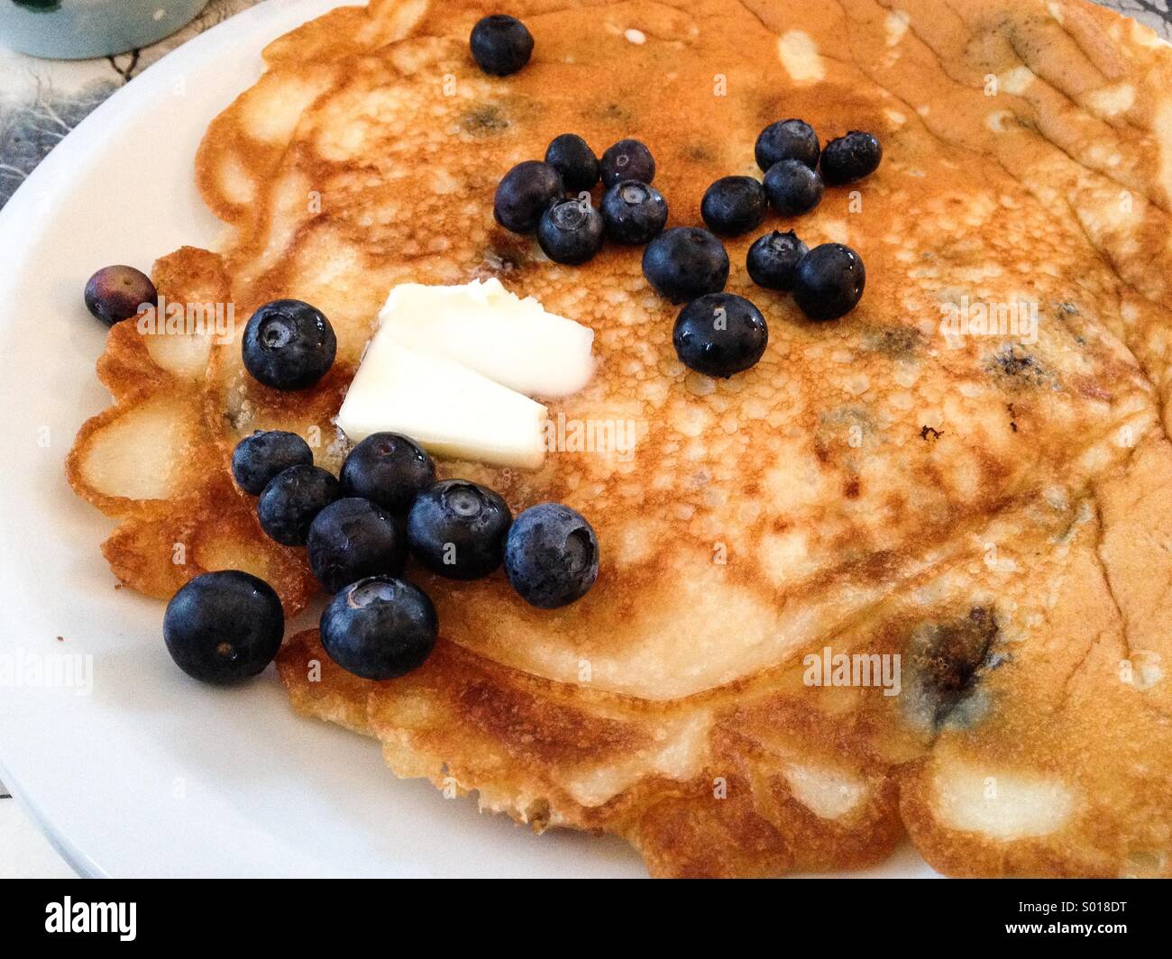 Fresh Blueberries on pancake with a pat of butter Stock Photo