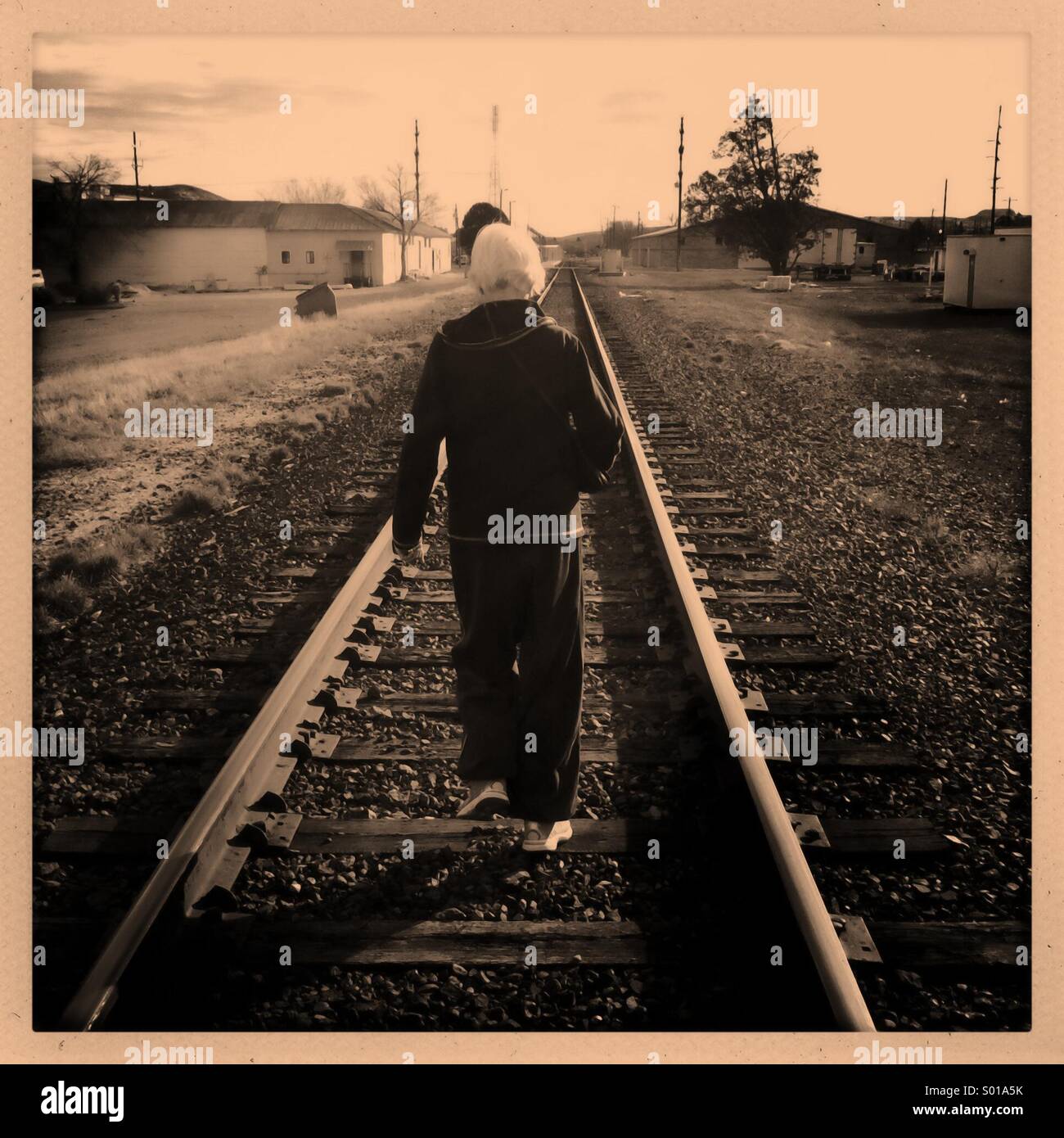 Elderly woman walking on railroad tracks. Stock Photo