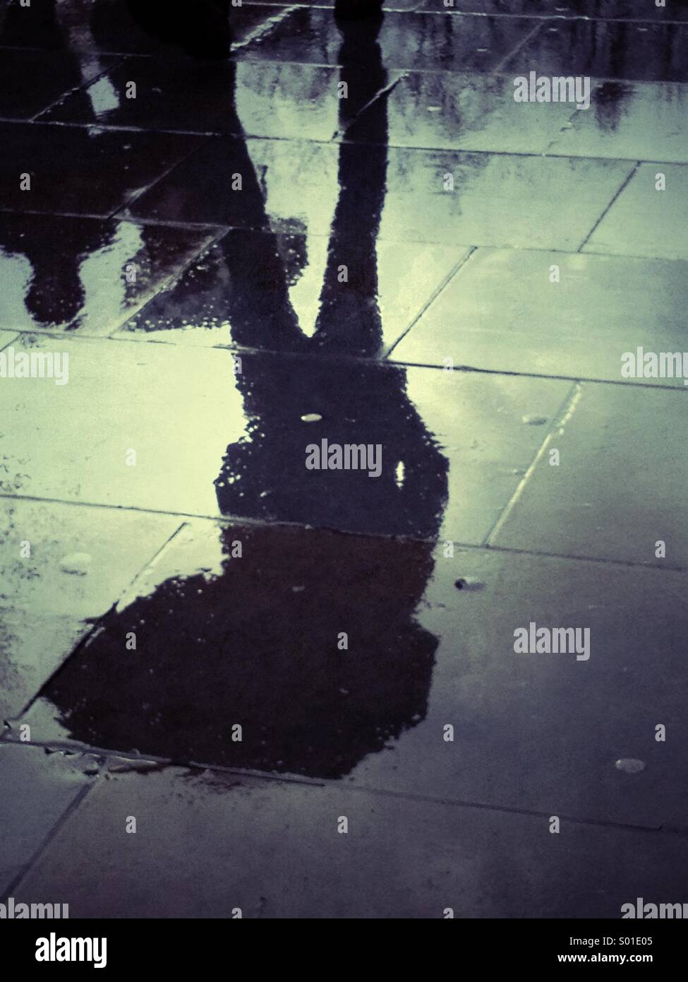 Reflection of a person carrying an umbrella on a rainy day in London - Smartphone Captured Stock Image
