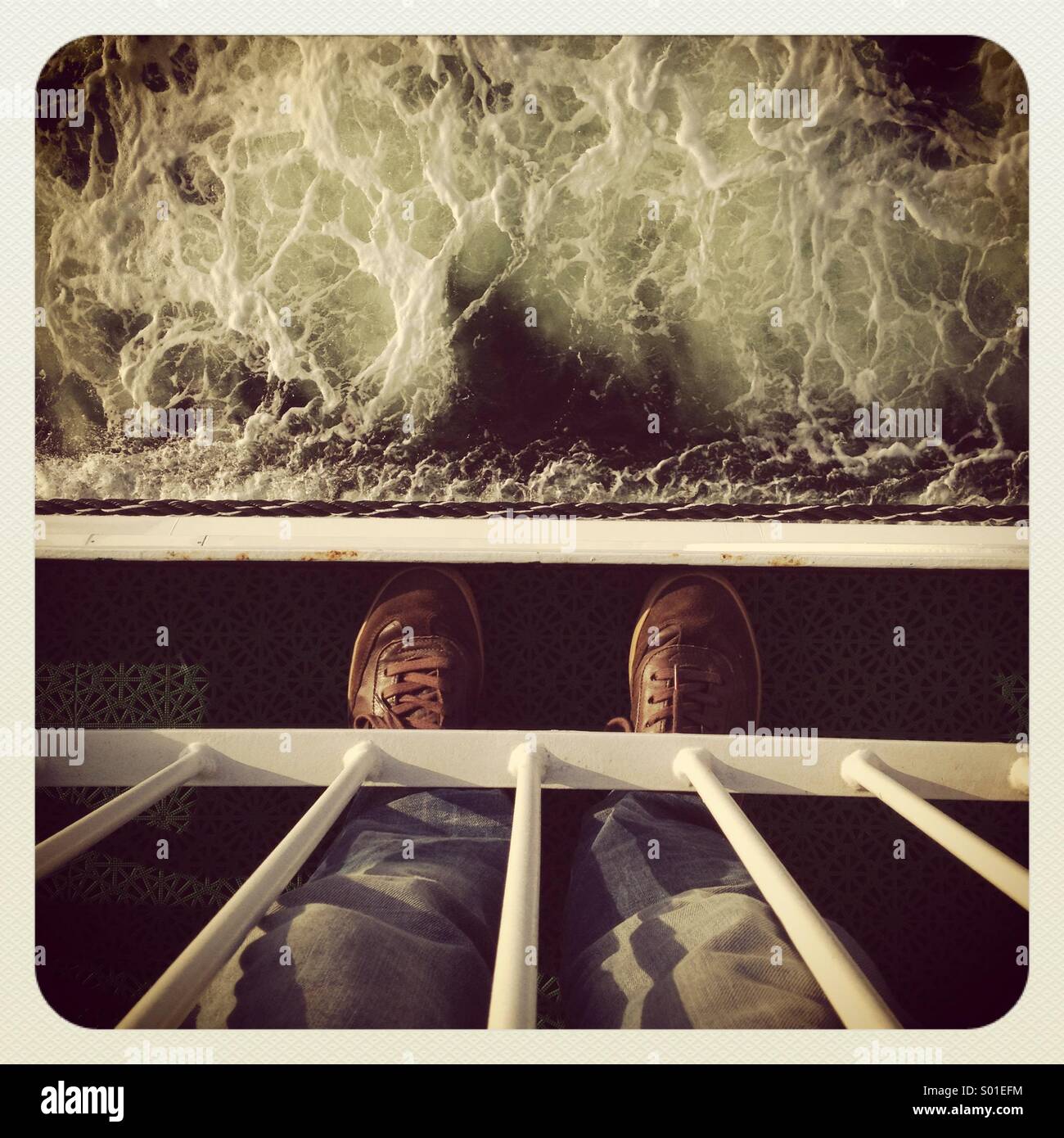 A man standing on the deck of a ship in a storm staring down into the waves POV - Smartphone Captured Stock Image