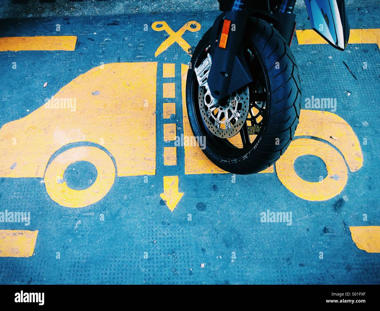 A street Art stencil of a car being cut in half with a motorbike wheel parked on it Stock Photo