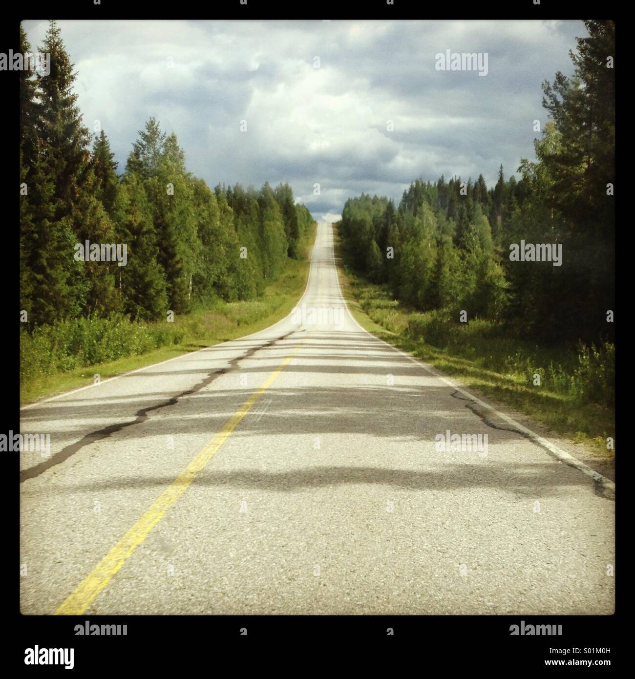 A dead straight cracked highway in the Finland wilderness - Smartphone Captured Stock Image
