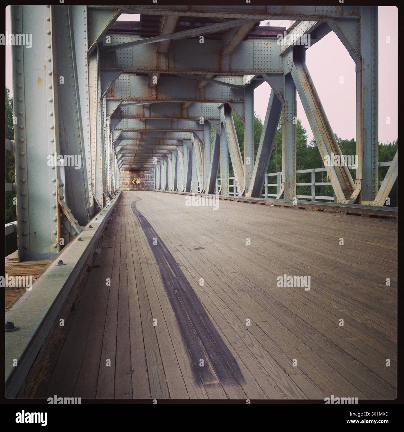 A box girder railway bridge public road in the Finnish wilderness with a single skid mark - Smartphone Captured Stock Image