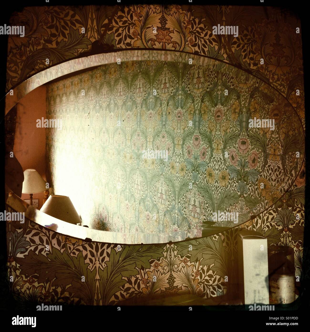 A mirror on William Morris wallpaper. Stock Photo