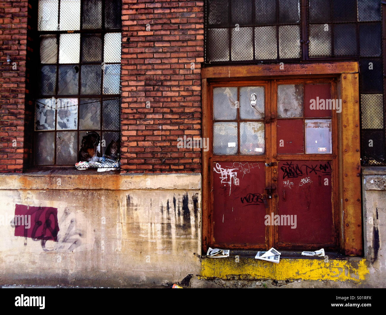 Windows and the door on a brick building are haphazardly painted over and run down - Smartphone Captured Stock Image