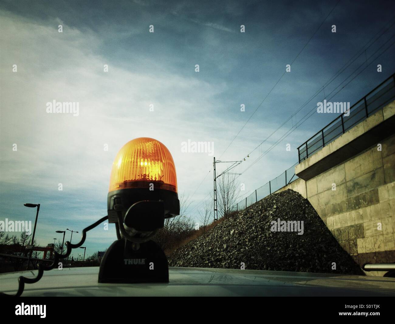 Orange warning light in industrial setting near train track. - Smartphone Captured Stock Image