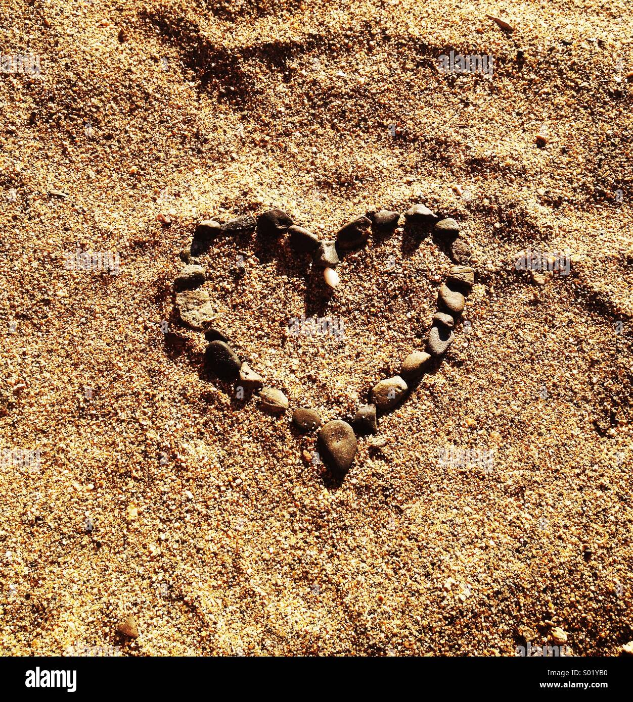 Heart made of pebbles in the sand. - Smartphone Captured Stock Image