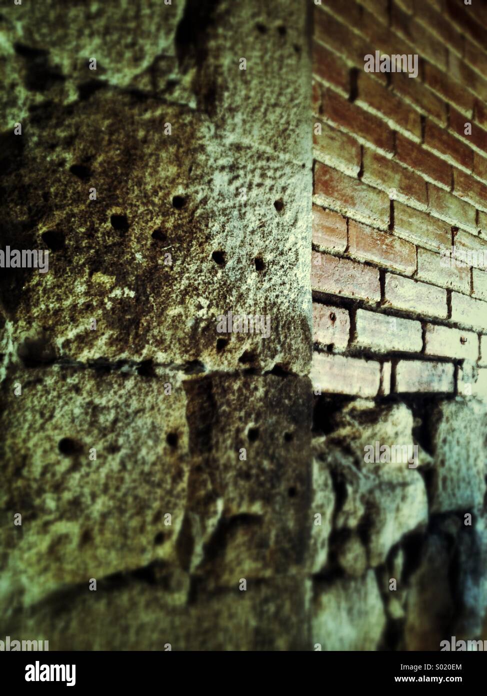 Old stone wall with holes and bricks Stock Photo