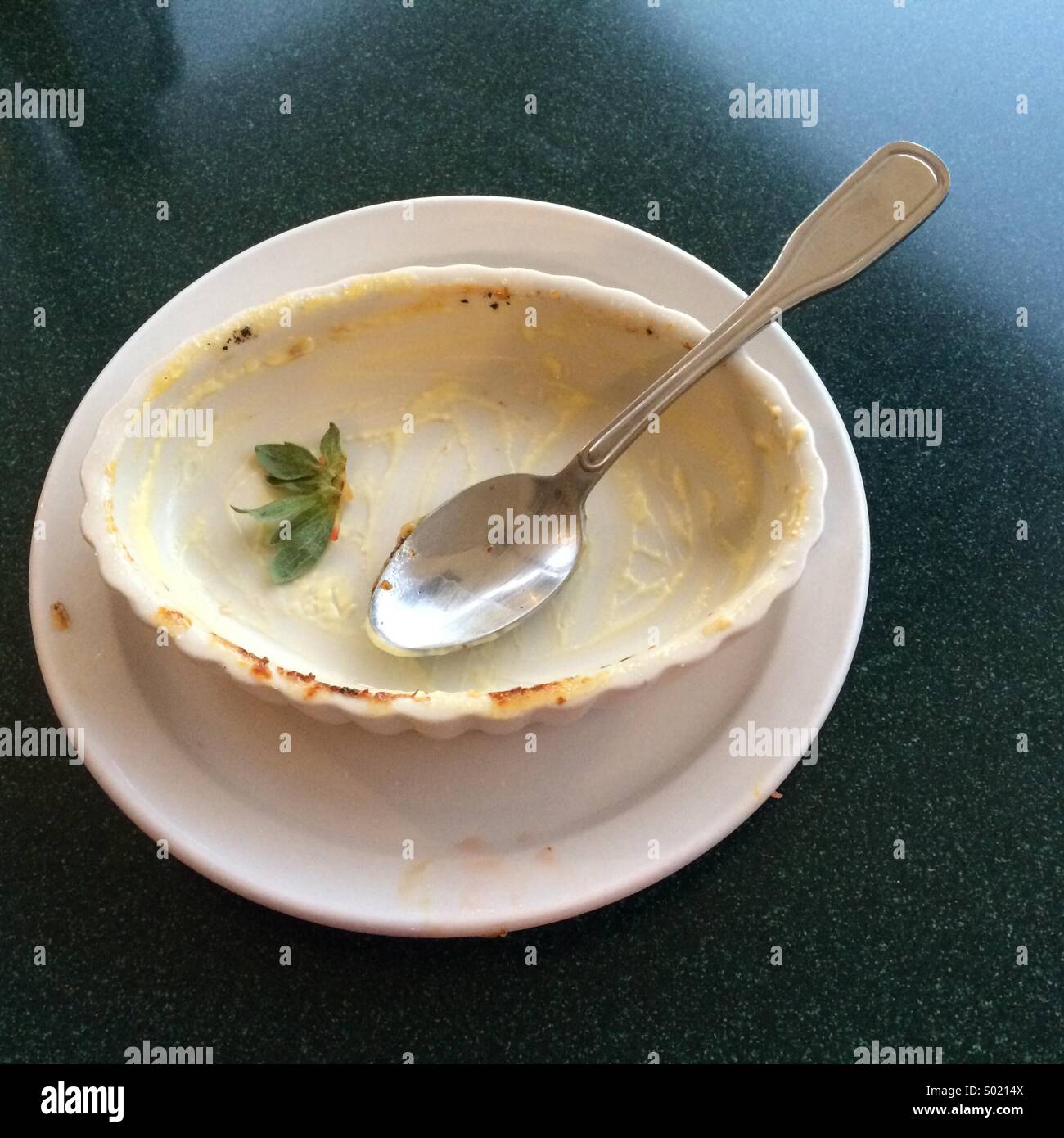 Empty dessert dish with spoon and strawberry husk - Smartphone Captured Stock Image