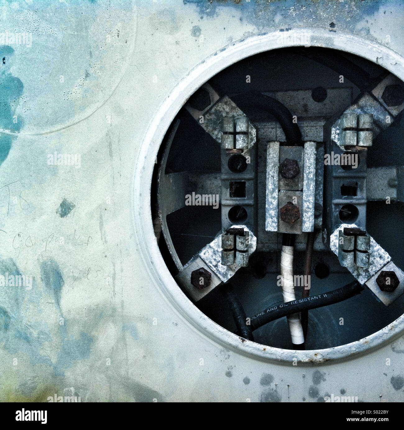 A hole containing electrical cords and components on a metal surface - Smartphone Captured Stock Image