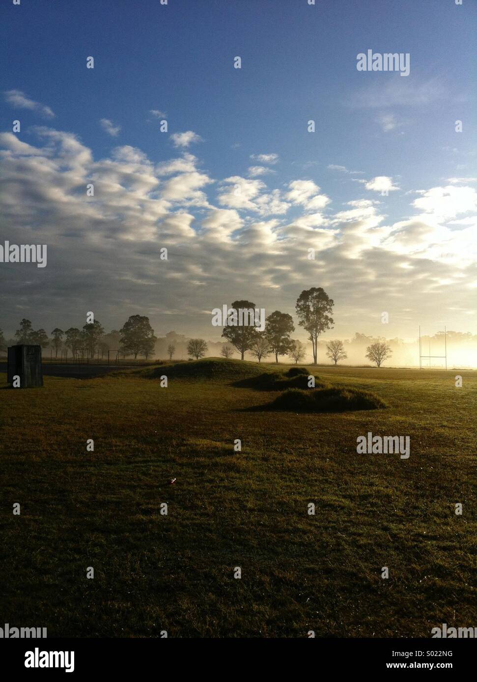 Early morning rural scene with cloudy sky and rugby goalposts Stock Photo