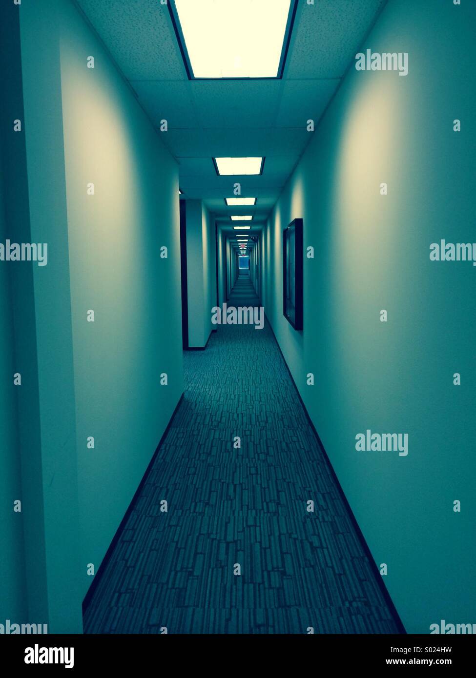 A long hallway fades to infinity in an office building Stock Photo