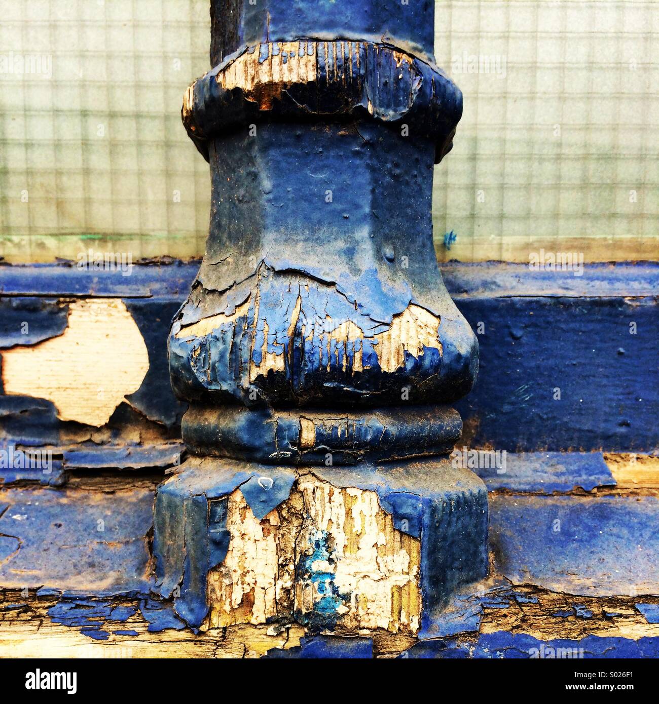 Peeling and flaking blue paint on an ornate window frame Stock Photo