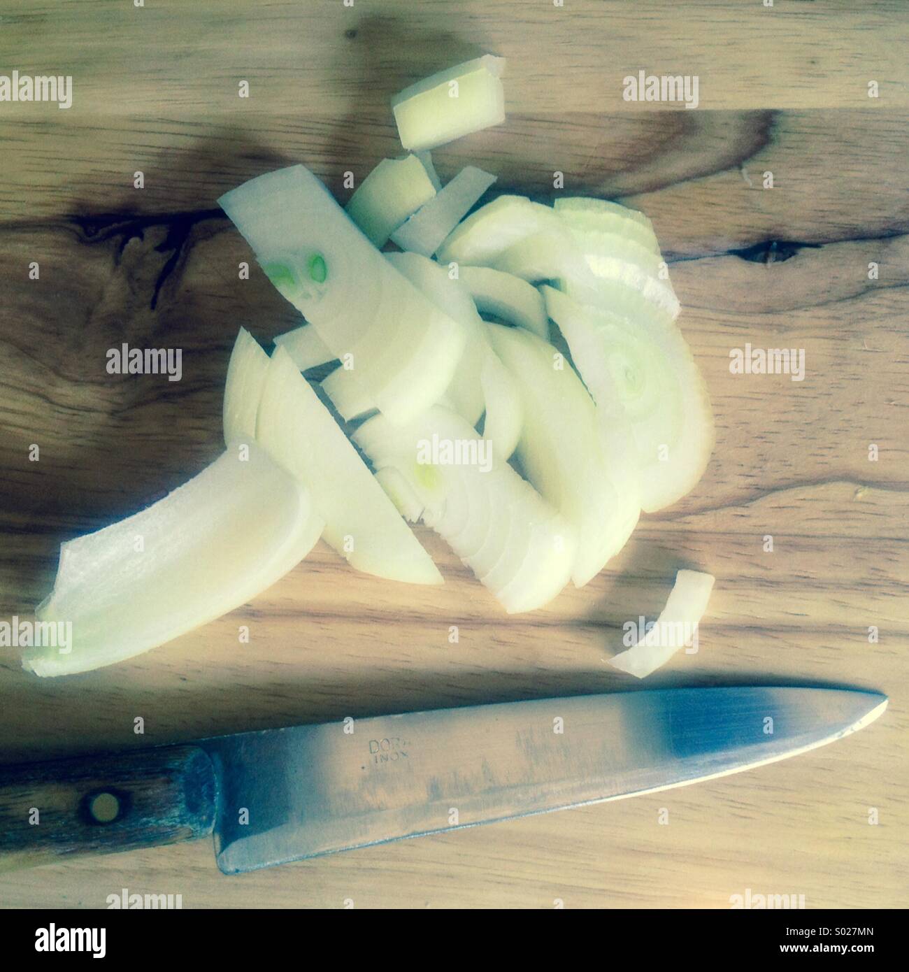 Knife and onion on wooden cutting board Stock Photo