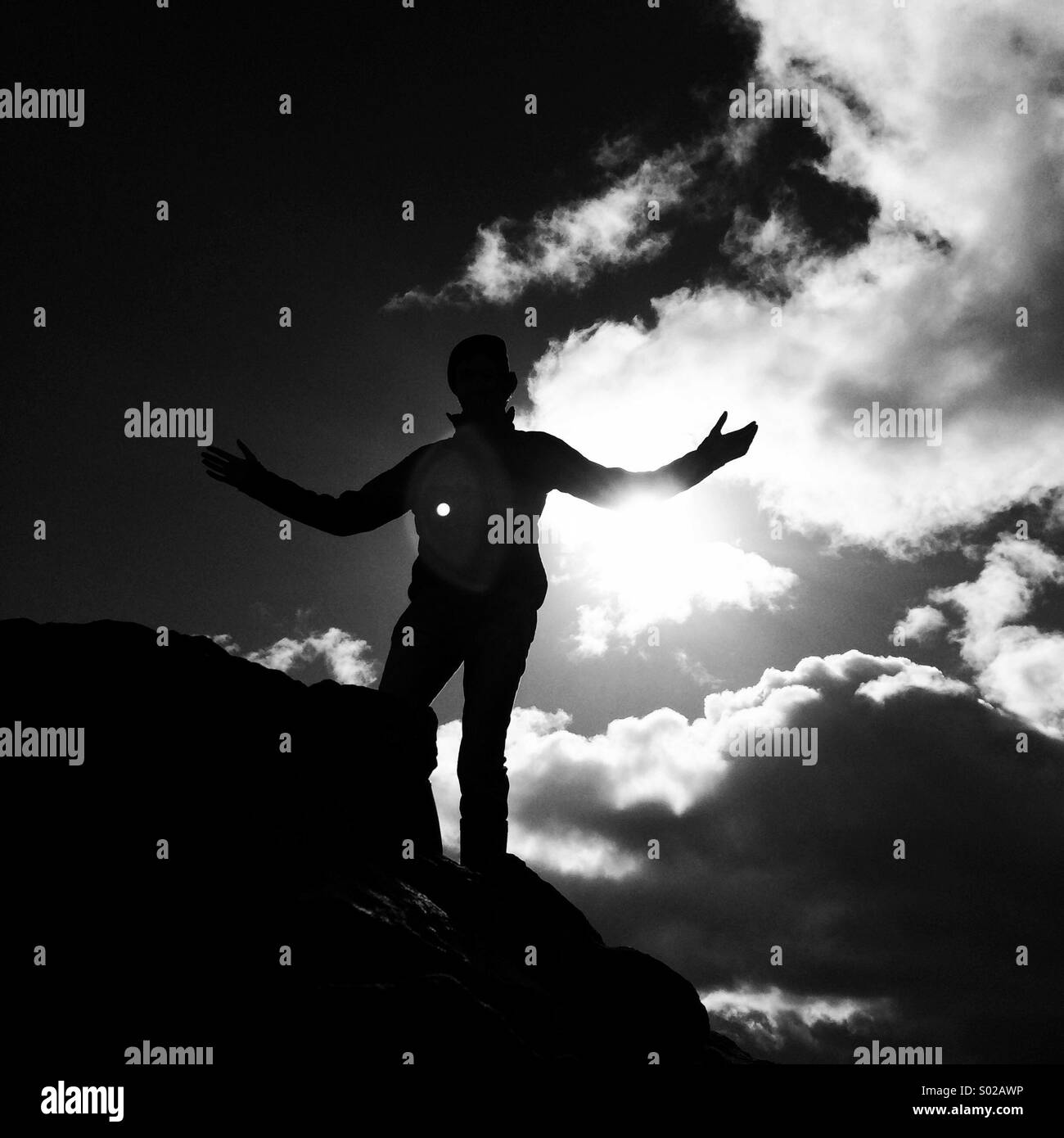 Silhouette of man on rock Stock Photo