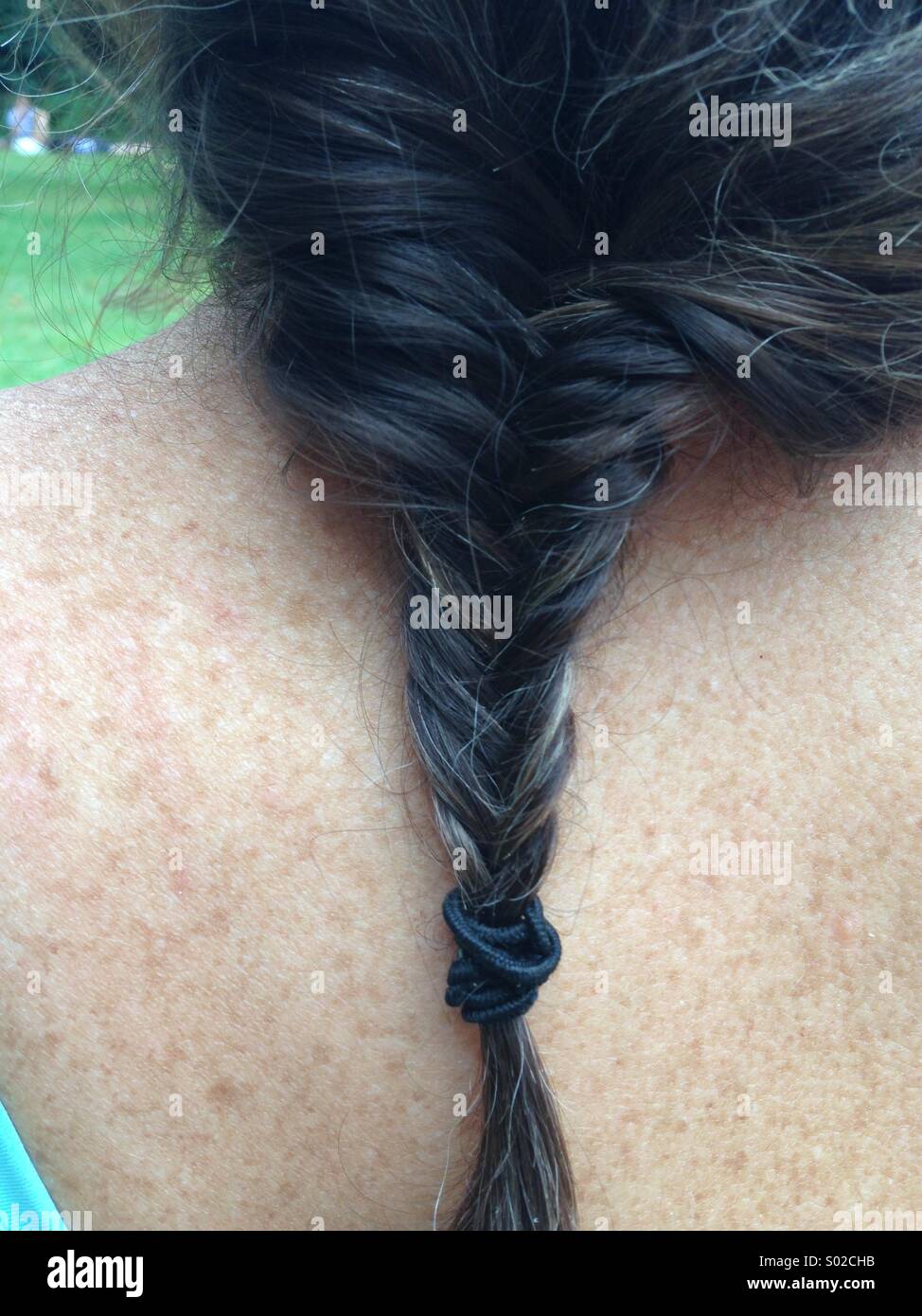 Hair in plait on woman's back with freckles Stock Photo