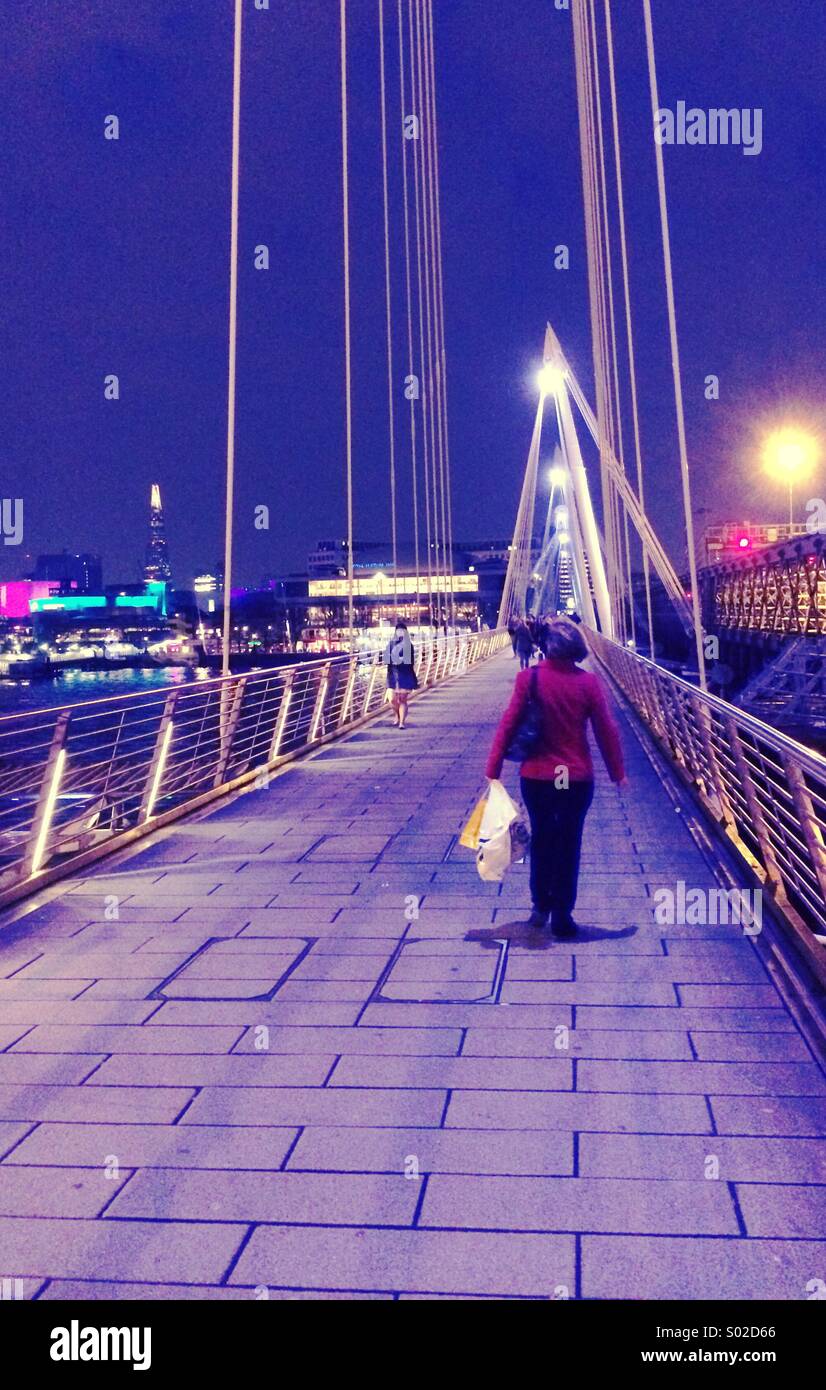 Woman walking on Hungerford bridge London UK at night - Smartphone Captured Stock Image