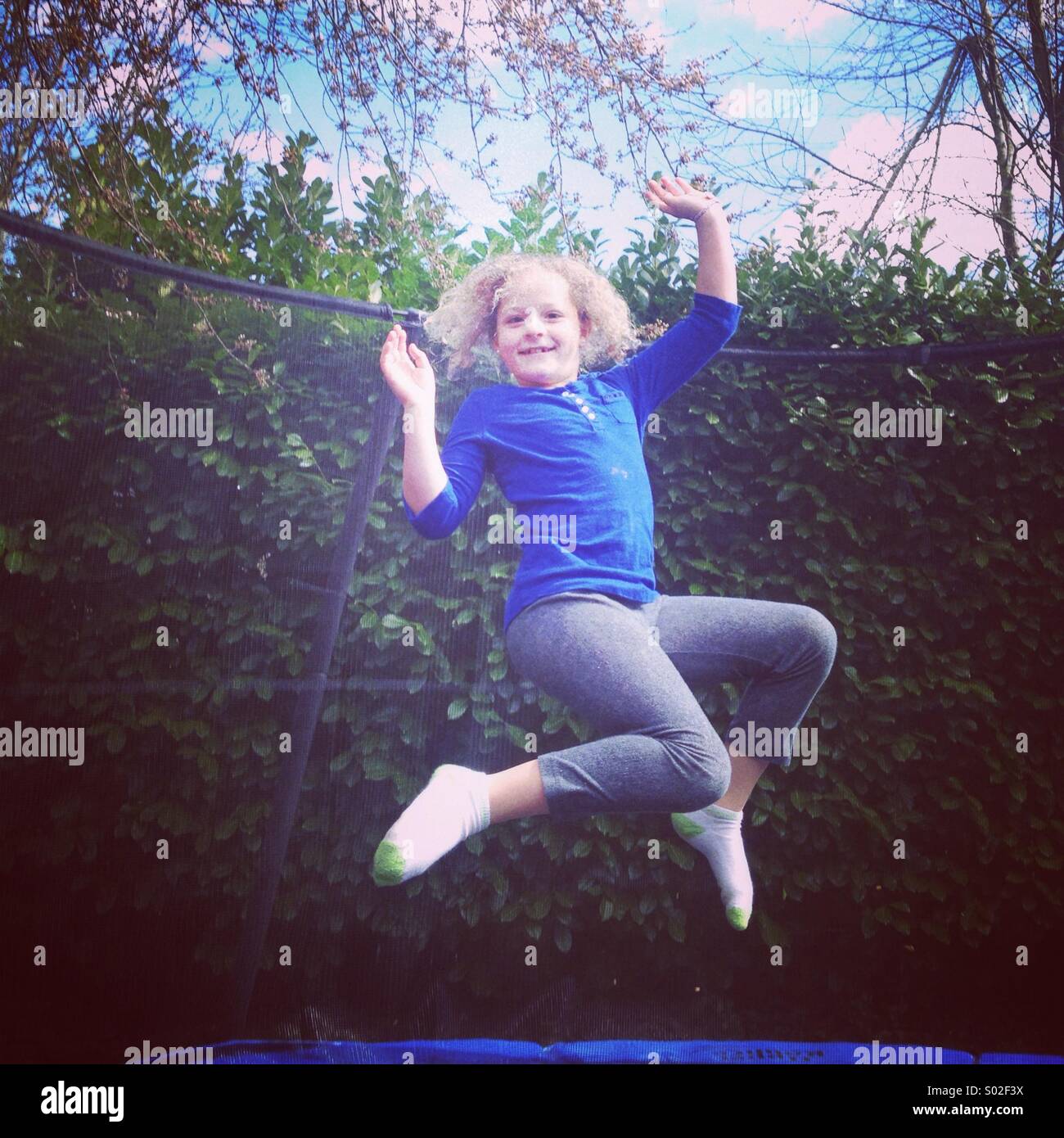 Girl, aged 9, jumping on trampoline. Stock Photo