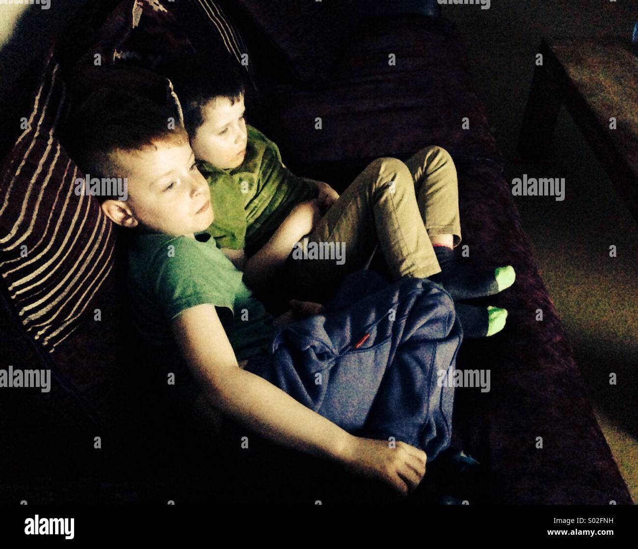 Young children watching a movie Illuminated by the light from the screen Stock Photo