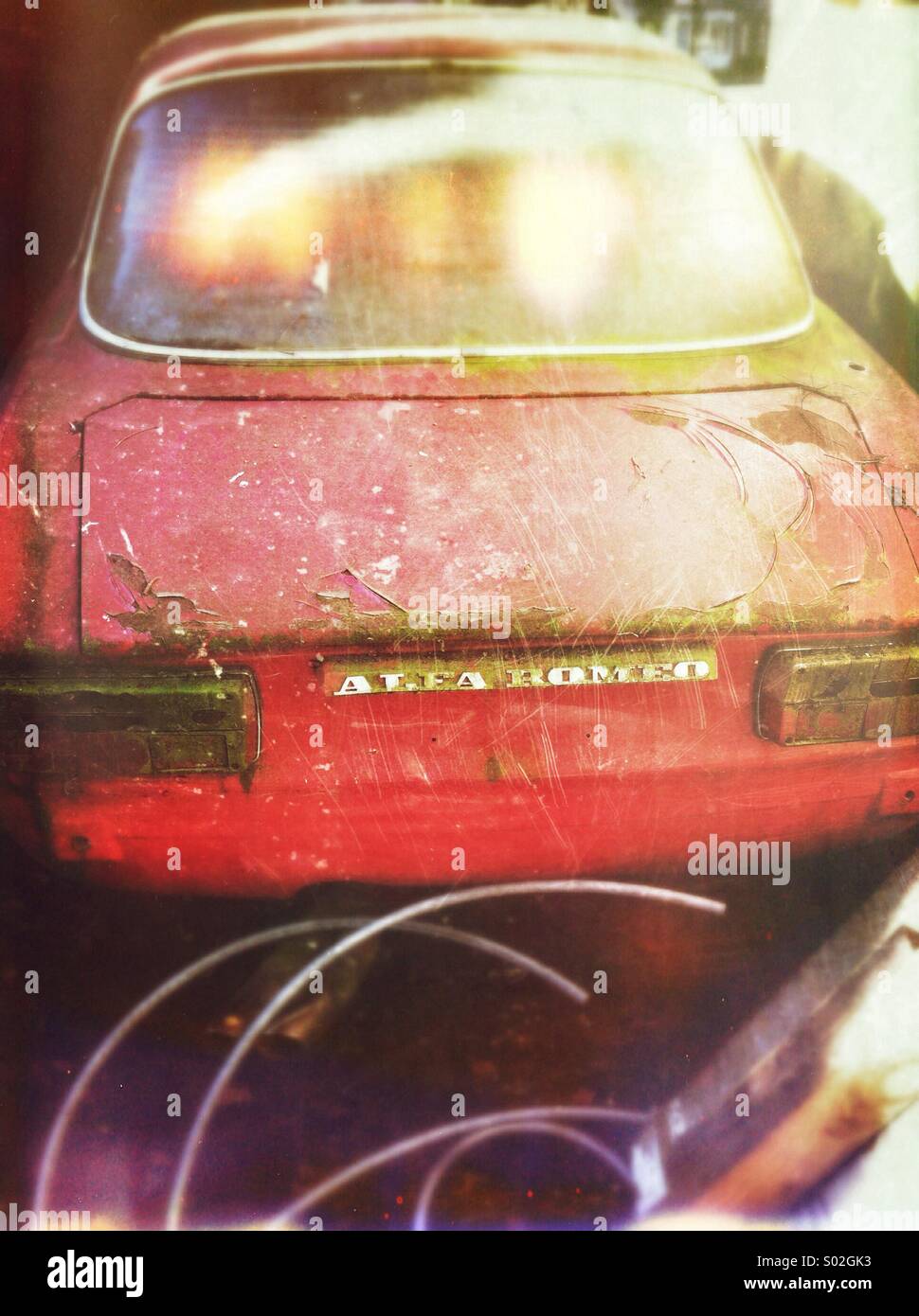 Old neglected Red Alpha Romeo sports car, long parked in the same spot and covered in moss. - Smartphone Captured Stock Image