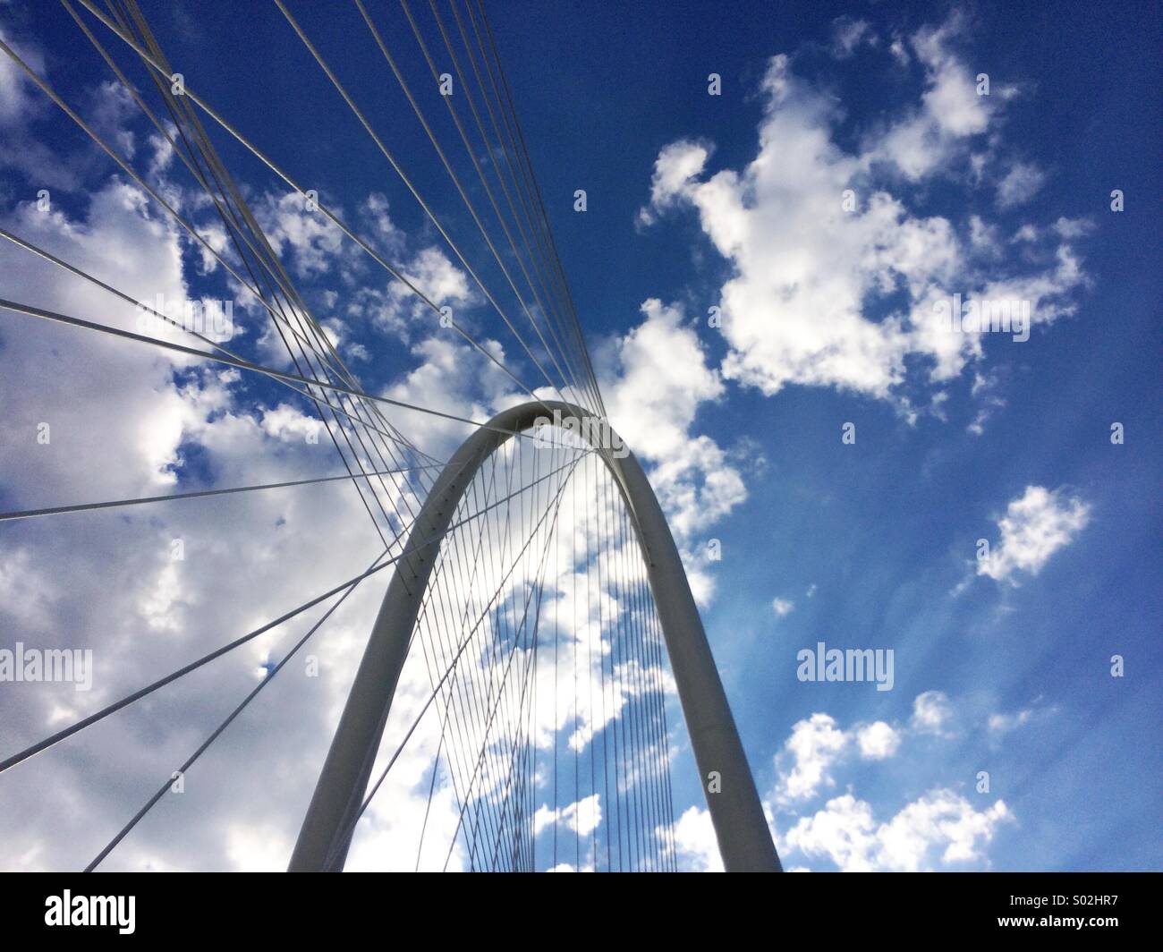 View of a blue sky with puffy white clouds and the Margaret Hunt Hill Bridge designed by Santiago Calatrava in Dallas, Texas. Stock Photo