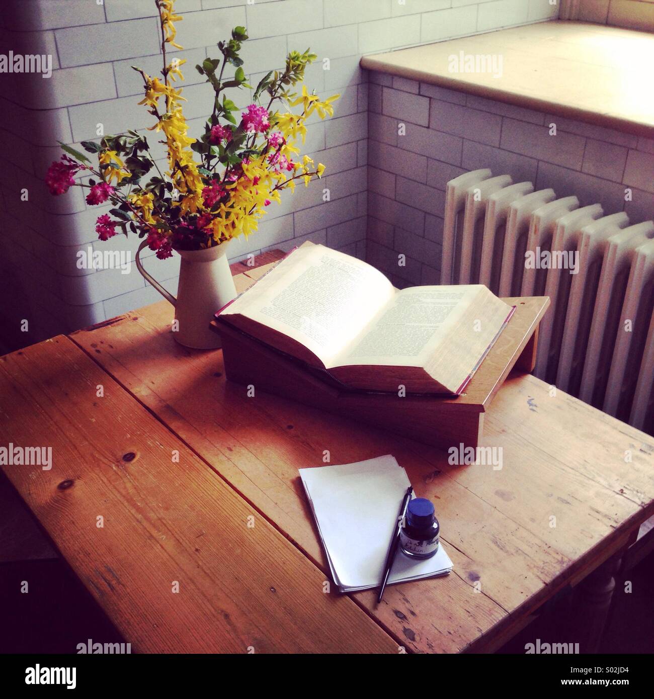 Flowers and pen and quill on a writing table by a window - Smartphone Captured Stock Image