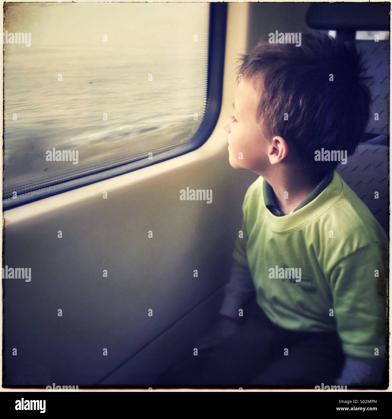 Little boy looking out a train window near Barcelona. Stock Photo