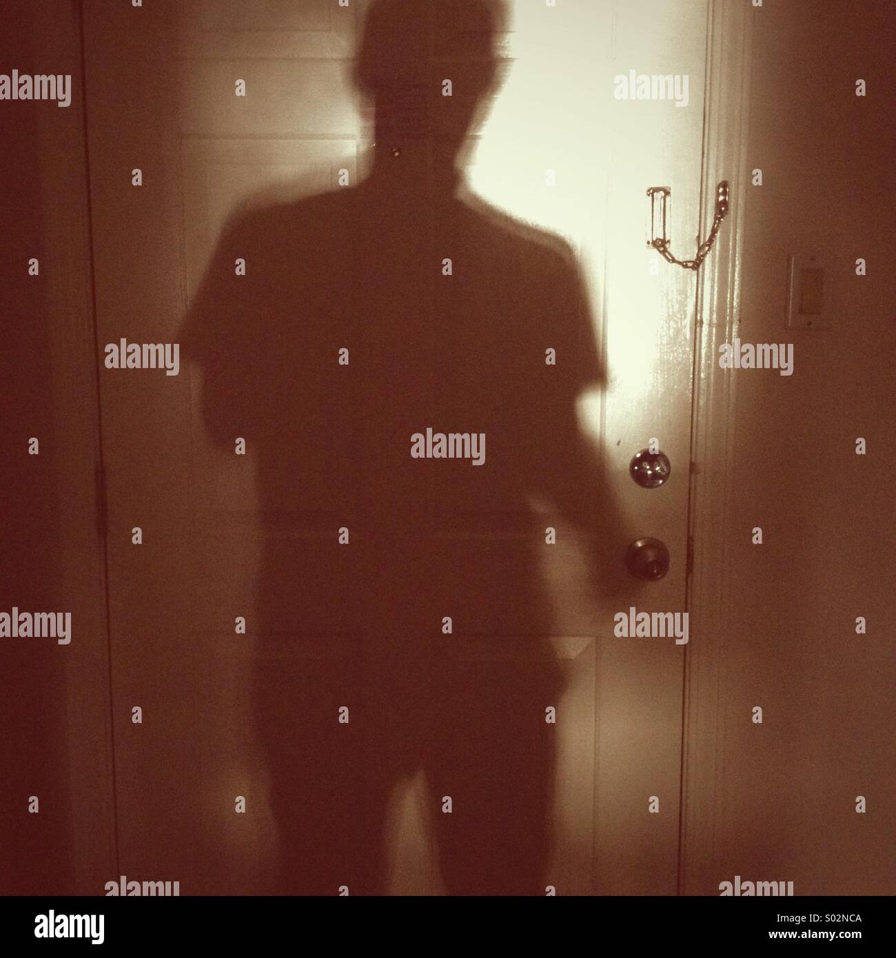 Shadow of man on locked door Stock Photo
