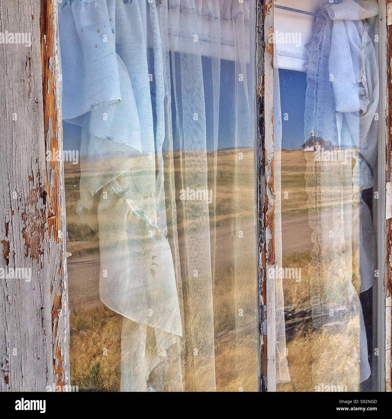 Old church is reflected in the window of the abandoned Milwaukee Road depot in Ringling Montana - Smartphone Captured Stock Image
