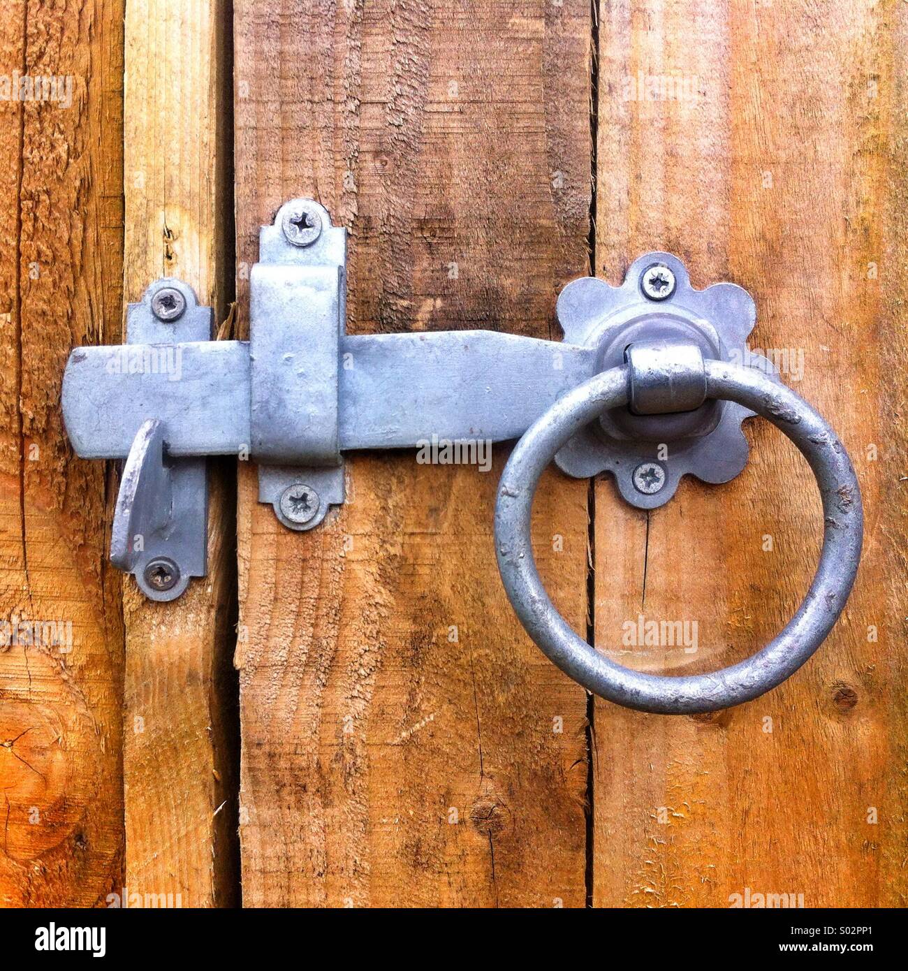 Rustic metal latch and ring on a wooden door with weathered boards and simple lock mechanism - Smartphone Captured Stock Image