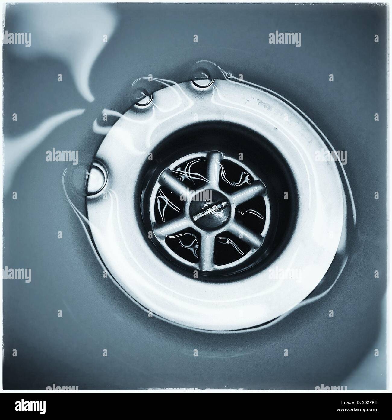 Water running down the plug hole in bathroom sink Stock Photo