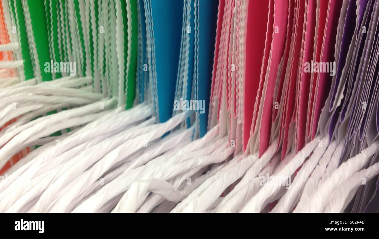 Row of colored bags with patterned edges and soft white fabric handles on display in supermarket Stock Photo