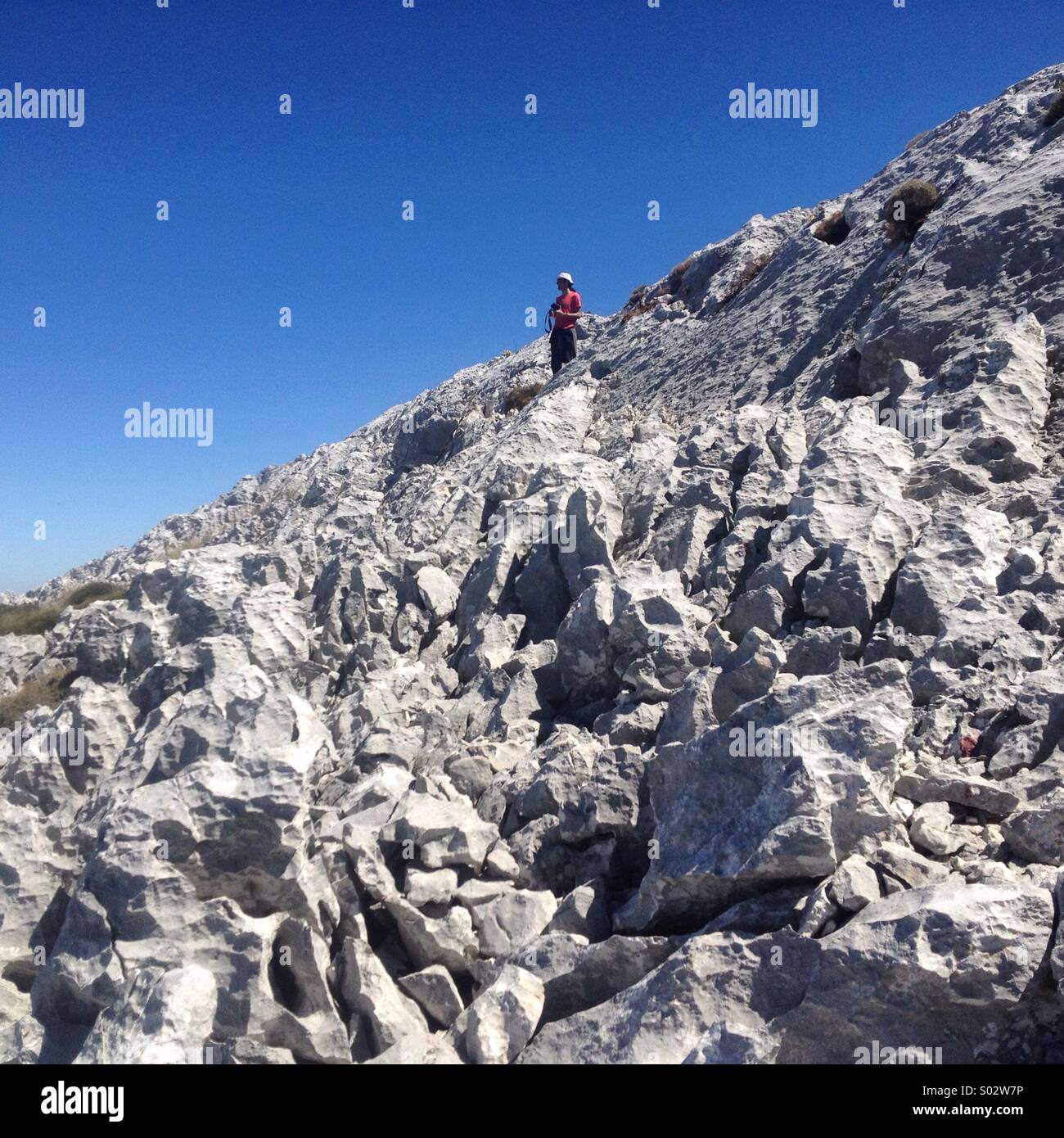 A tourist walks on the peak of the Simancon mountain in the Parque Natural Sierra de Grazalema natural park, Grazalema, Cadiz province, Andalusia, Spain - Smartphone Captured Stock Image