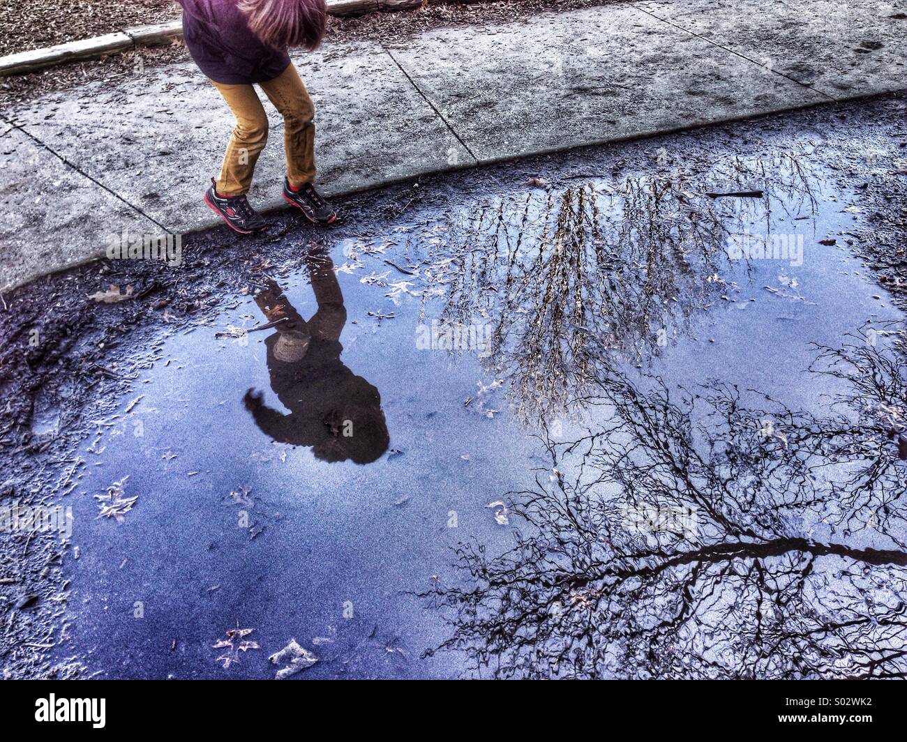 Boy and trees reflected in puddle of water - Smartphone Captured Stock Image