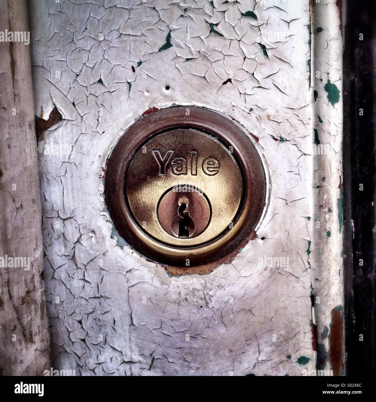 Yale lock on a flaking neglected door - Smartphone Captured Stock Image