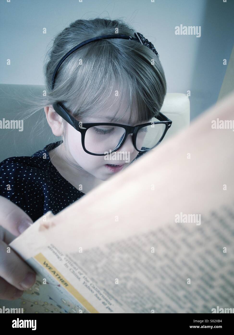 Little girl reading newspaper Stock Photo