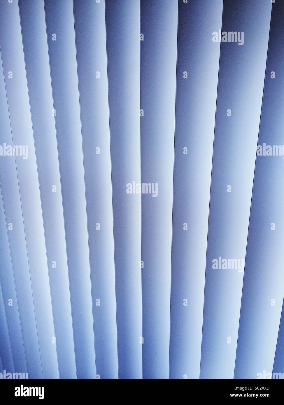 A vertical blind with closed slats in an apartment interior with blue light. - Smartphone Captured Stock Image