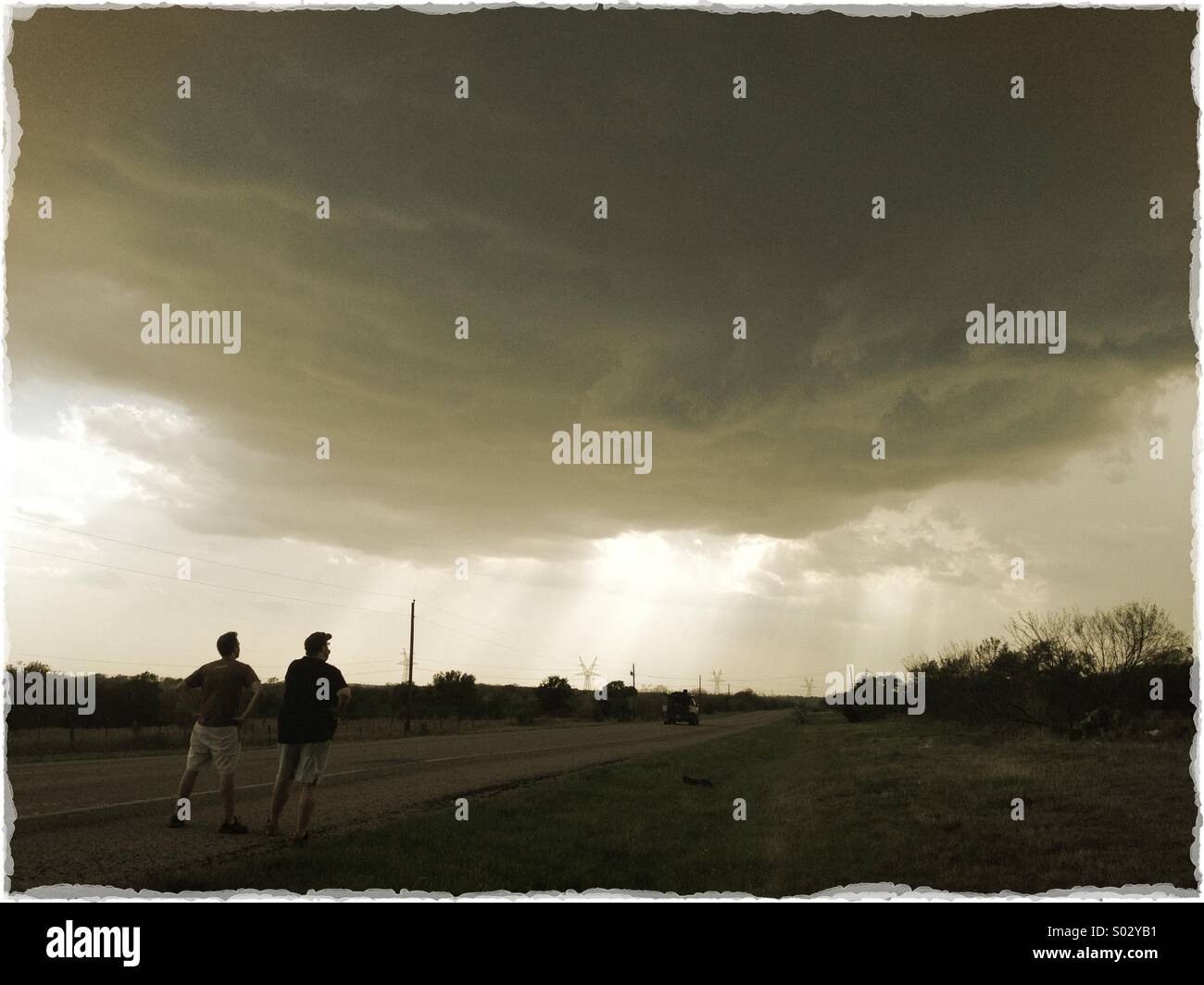 Two men looking at a dark and ominous storm cloud. Stock Photo