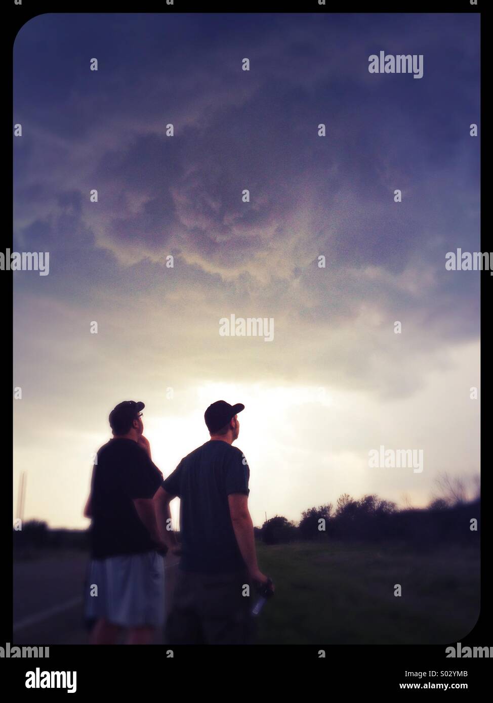 People looking up in the sky at a large storm cloud. Stock Photo