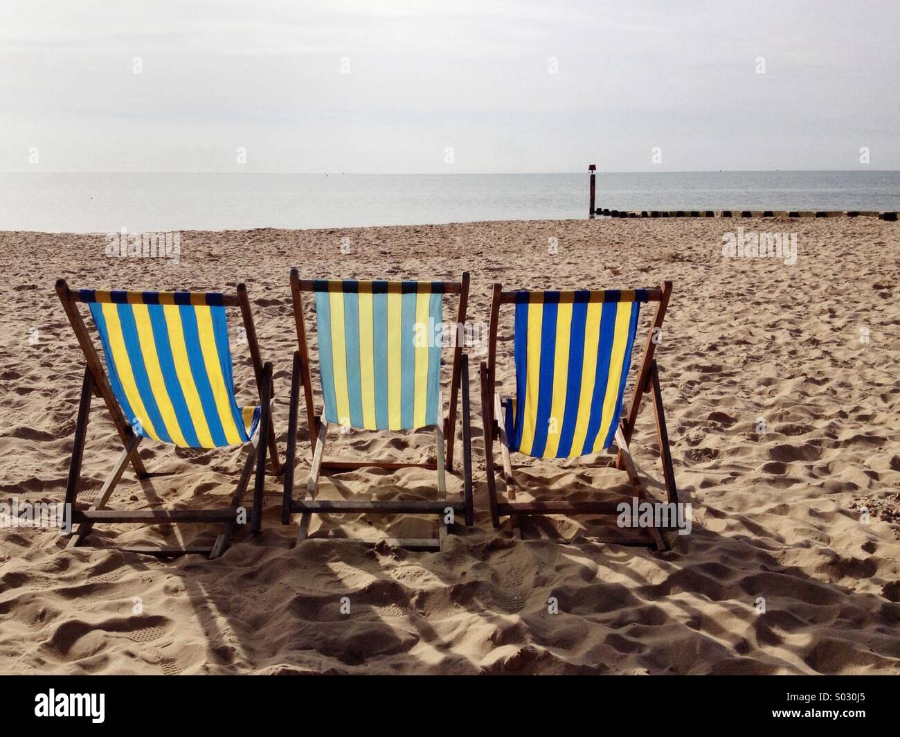 Three Deck chairs on Bournemouth West Beach, facing the sea, waiting