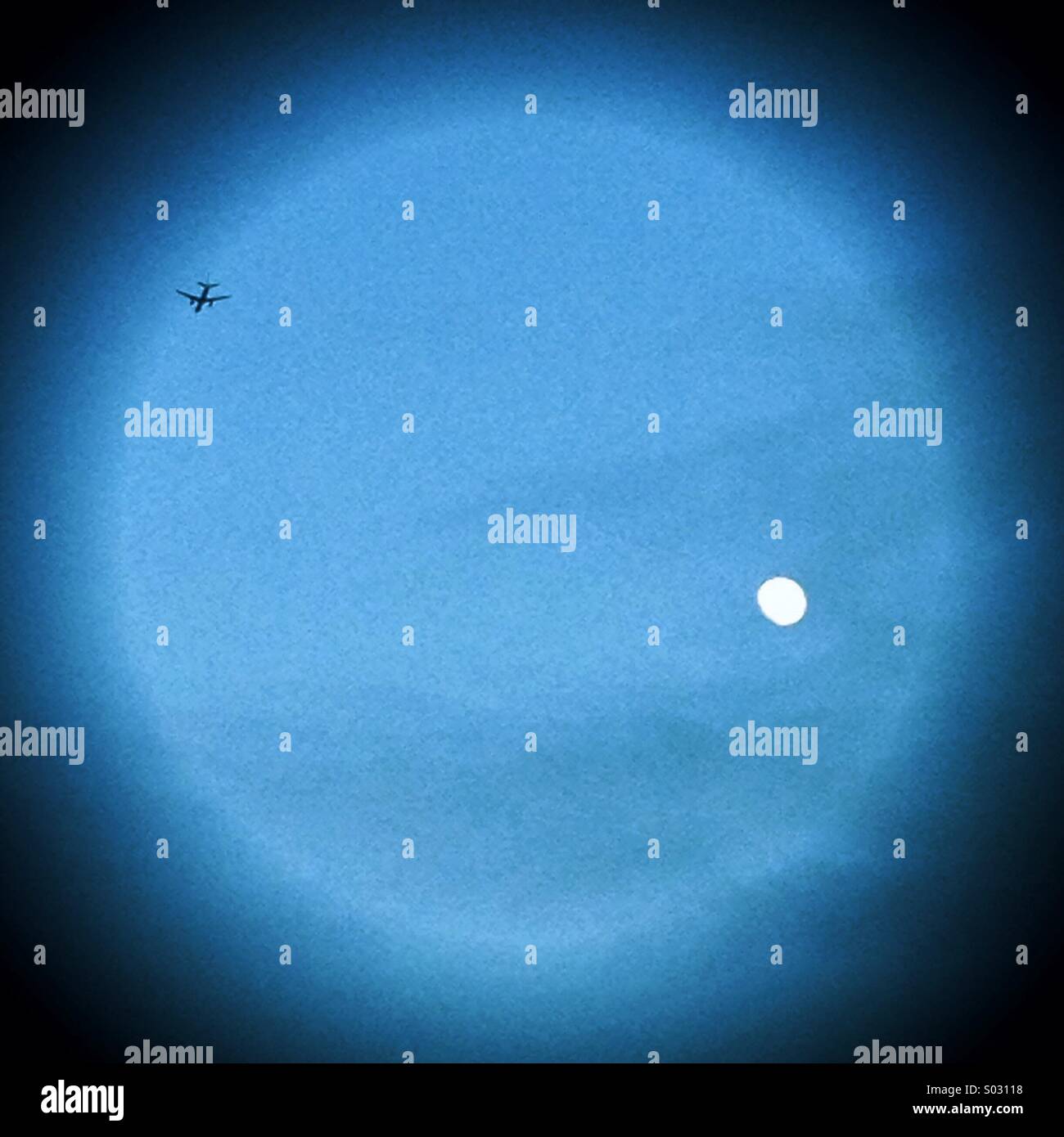 An aeroplane flies past the moon - Smartphone Captured Stock Image