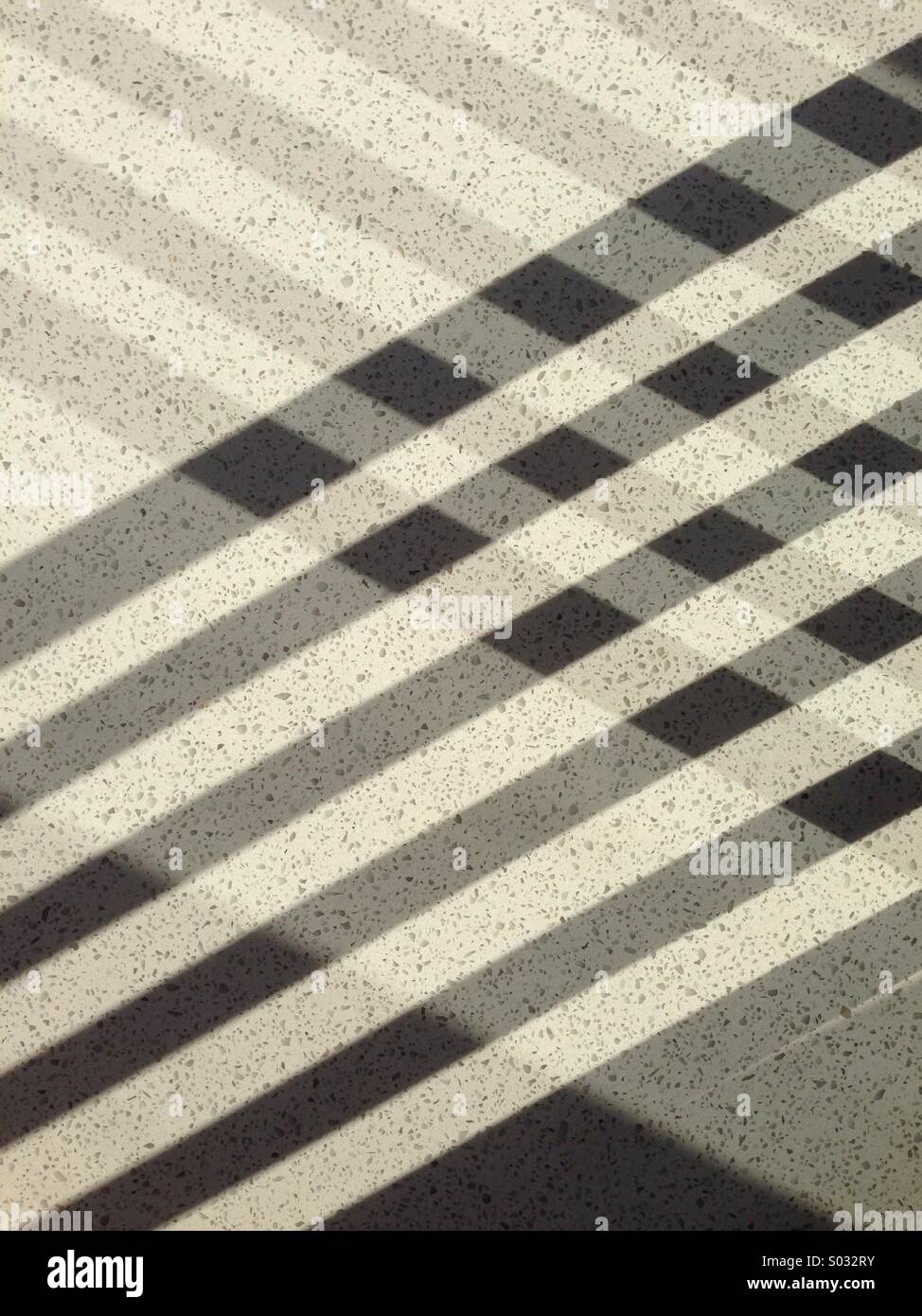 Table tartan: light shining and being reflected through chairs creates interwoven shadows on a quartz tabletop. - Smartphone Captured Stock Image